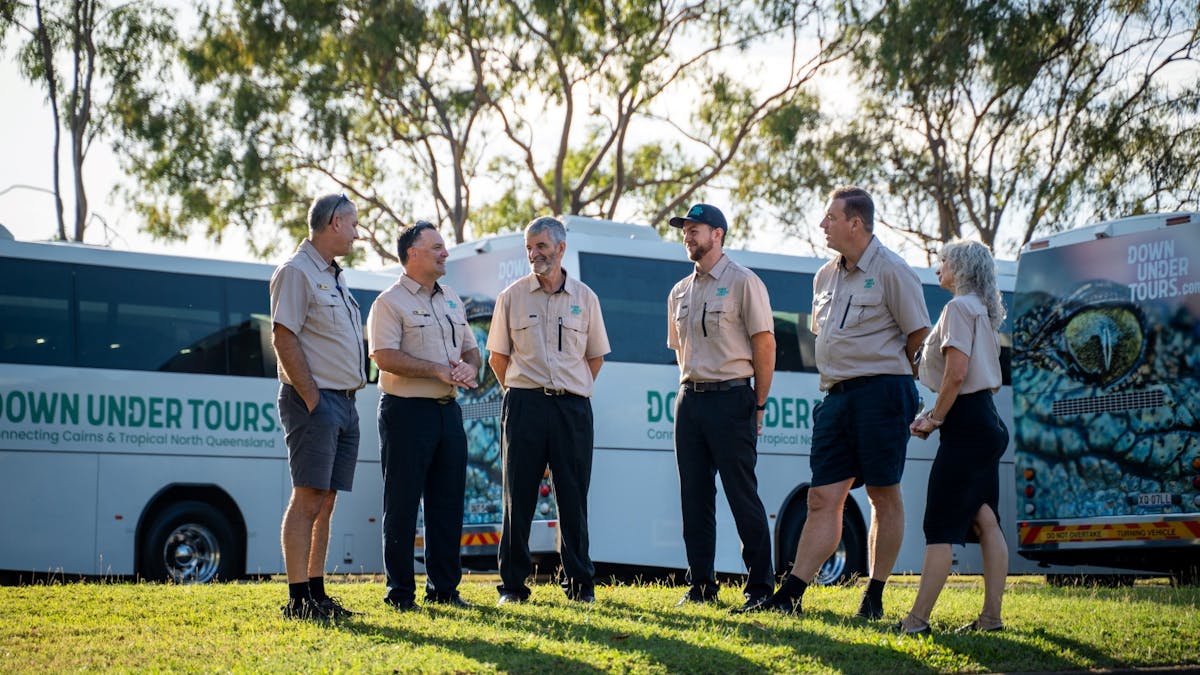 A group of driver guides meeting with three coaches in background