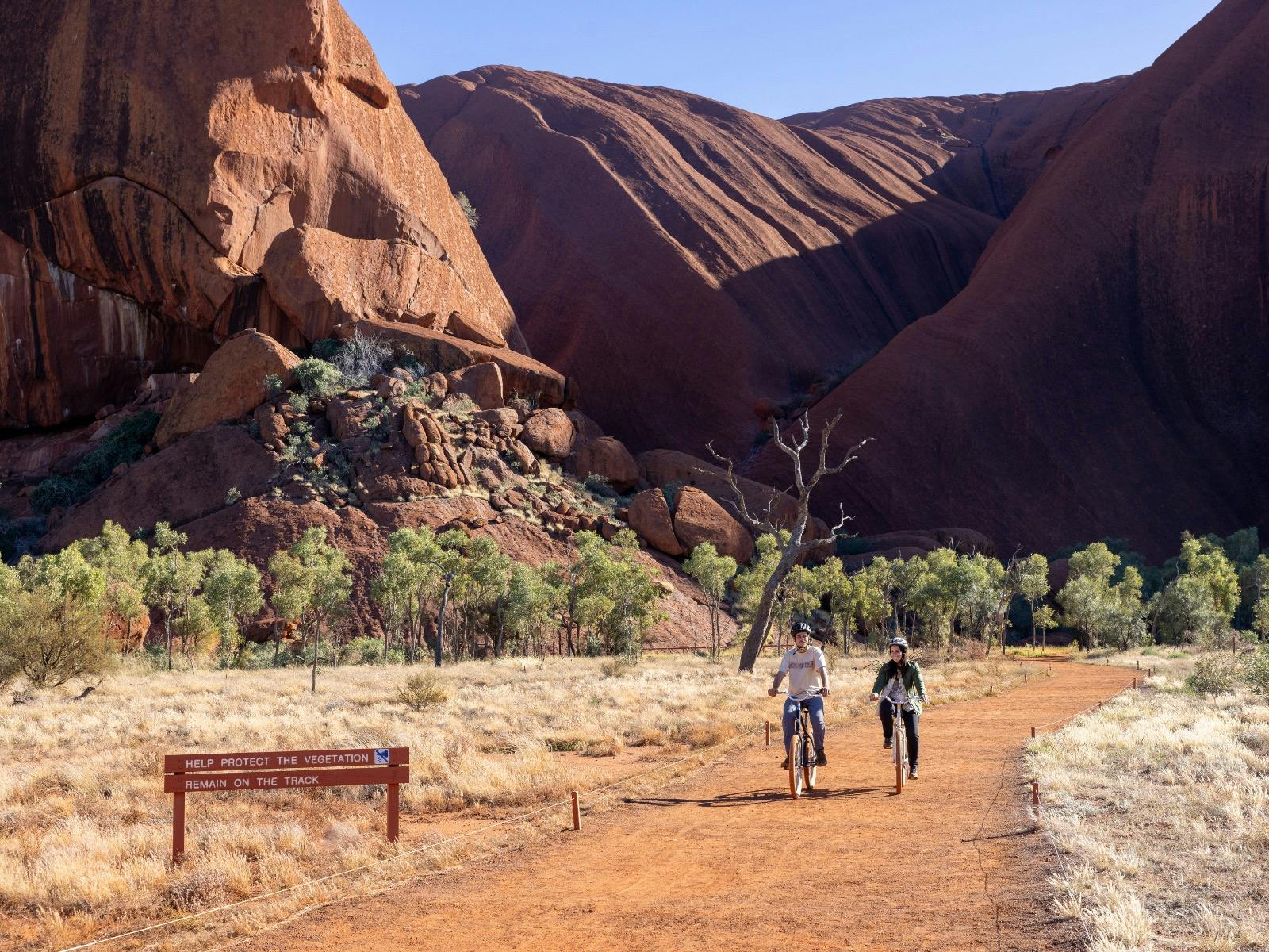 Two people cycling the base of Uluru