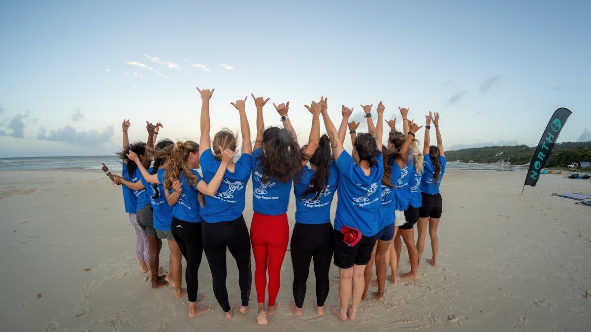 A group of happy girls together on the beach throwing shakas