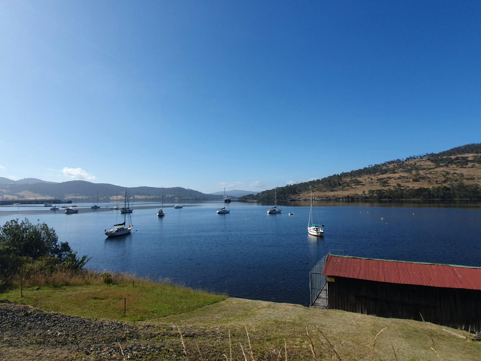 A view of the river with boats moored and a small boatshed