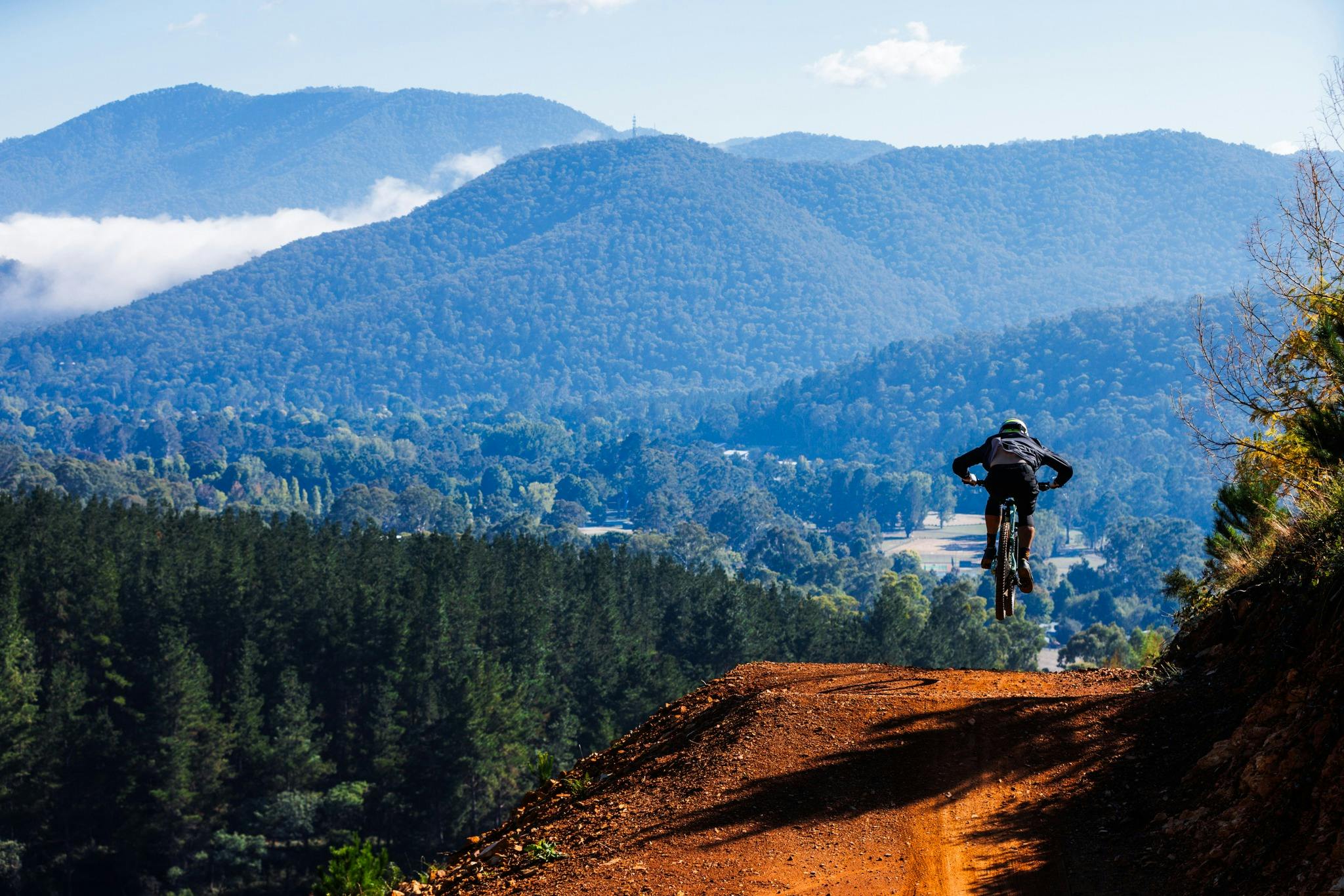 Bicycle Rider off road on jump trail with mountain back ground from bright victoria