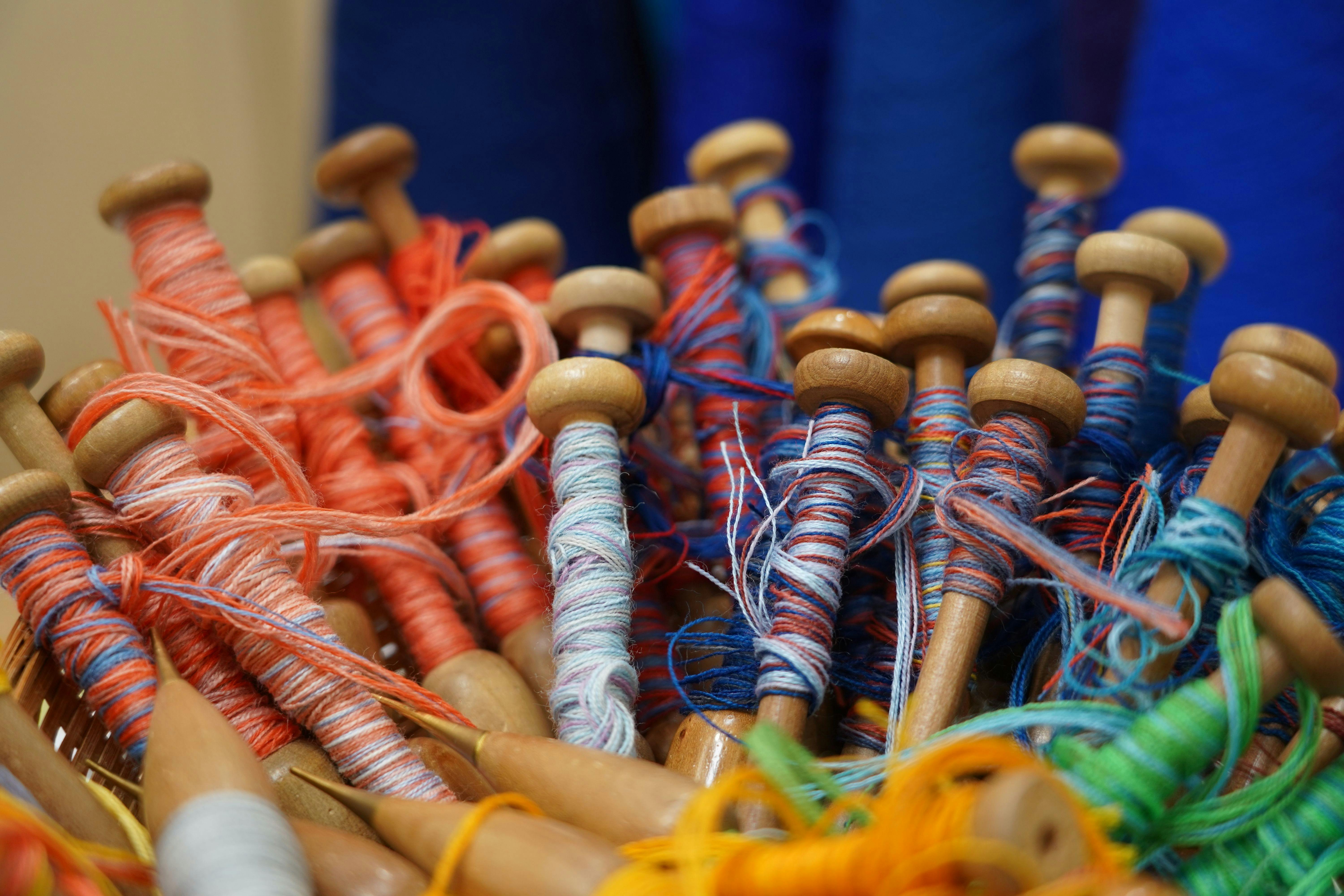 A close-up image of red and blue yarn on weaving bobbins