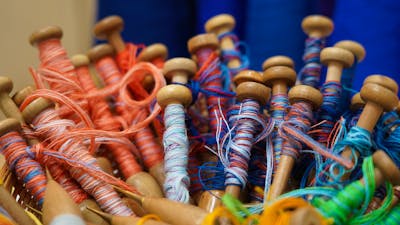 A close-up image of red and blue yarn on weaving bobbins
