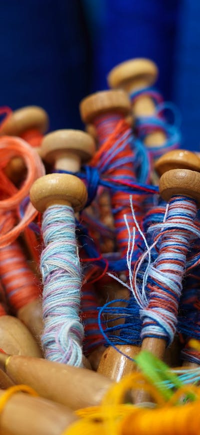 A close-up image of red and blue yarn on weaving bobbins