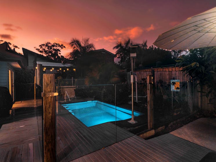 Accessible backyard of Seafarers Diamond Beach at dusk with a pink sky and blue pool