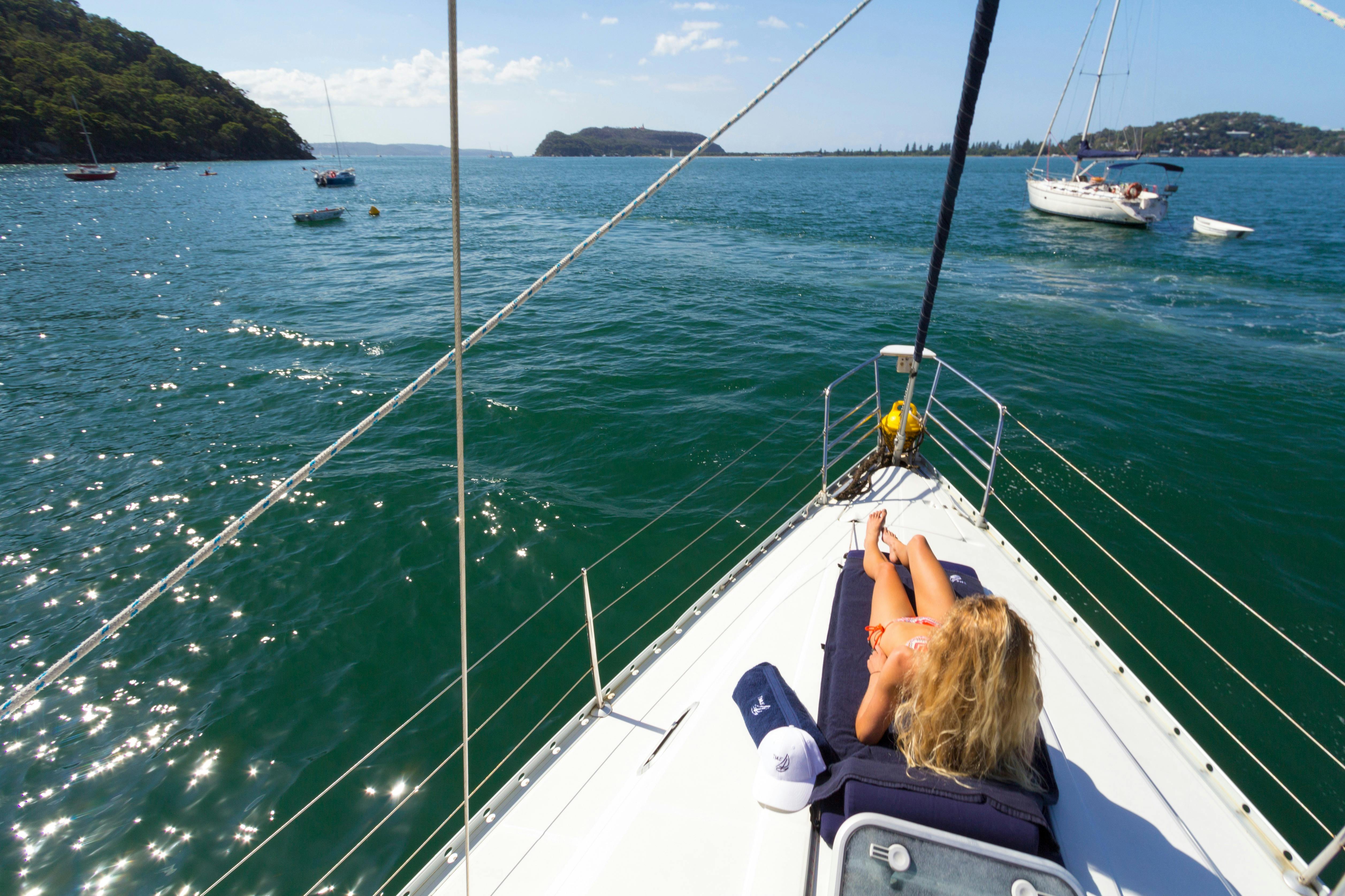 Lady relaxing on sunlounge on the bow of Taylor Made  Escapes yacht in beautiful Pittwater, Sydney