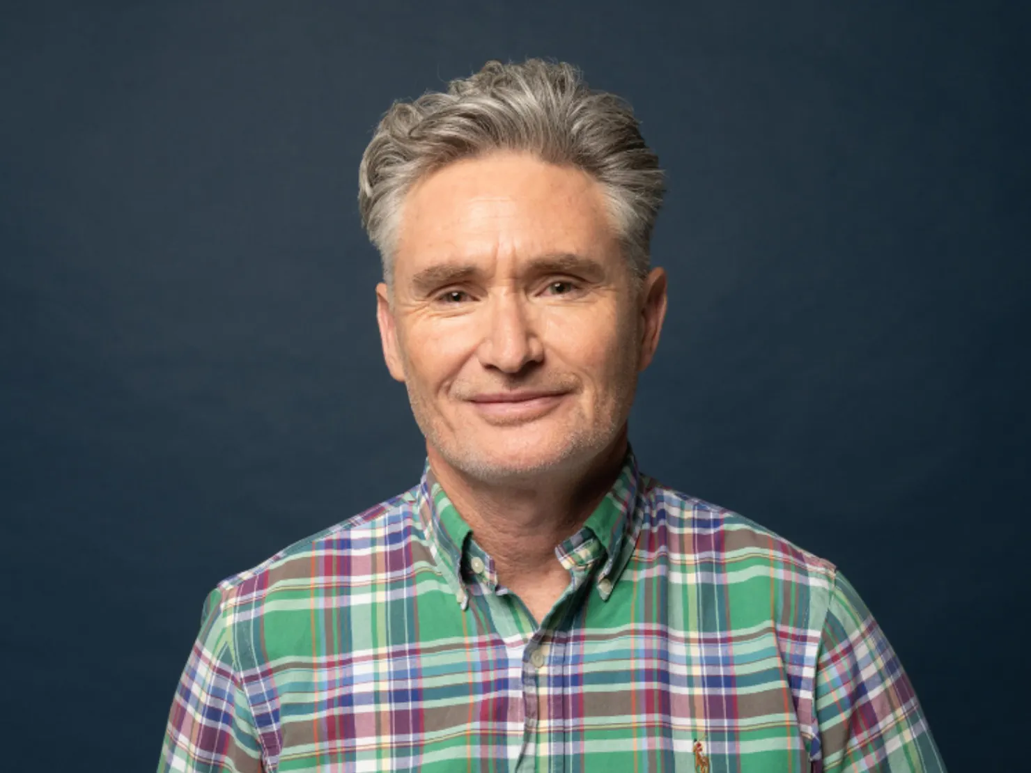 Dave Hughes in a green shirt in front of a dark background.