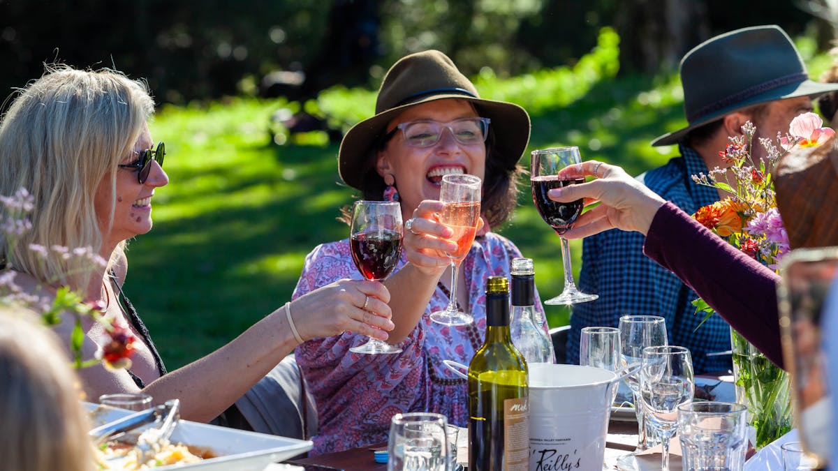 Wine cheers between 3 girls at a long lunch outdoors