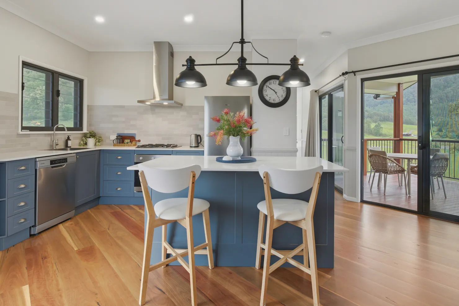 Modern lodge kitchen with island bench, stools, and sliding doors opening to deck views