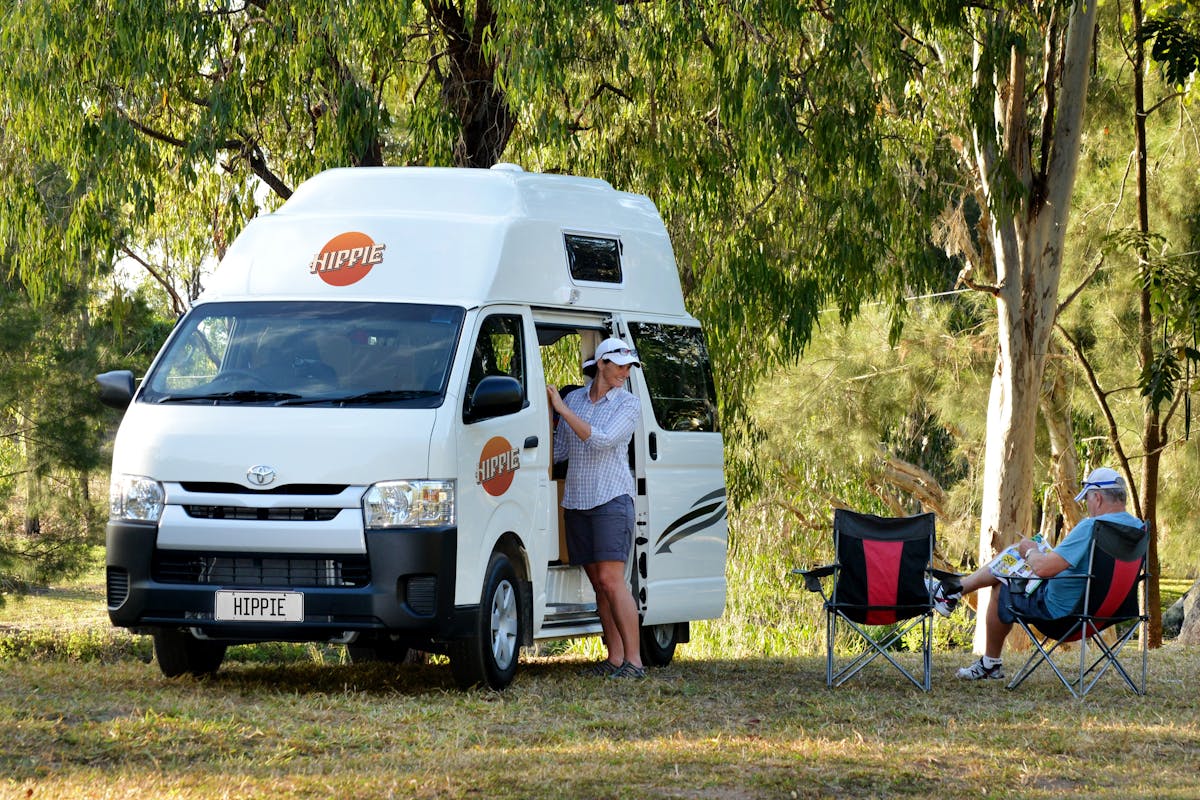 A woman smiles at her husband next to a Hippie Hitop Camper