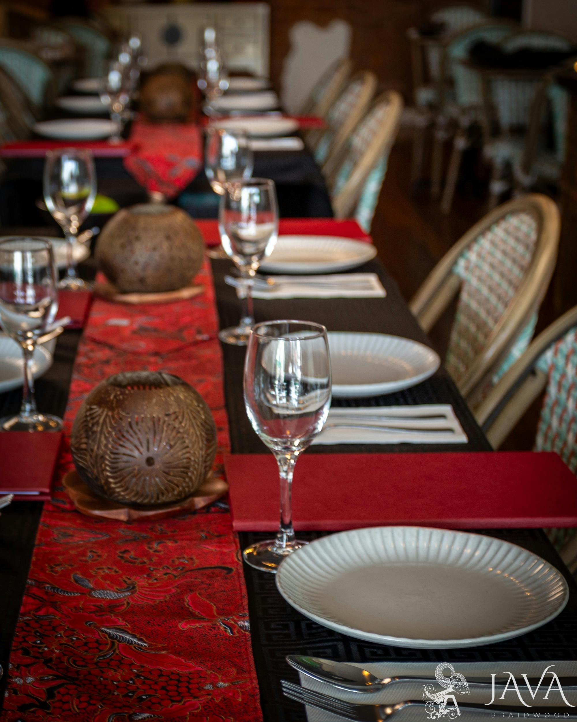 black tablecloth, red batik table runner, coconut shell carved candles and rattan chairs, warm light