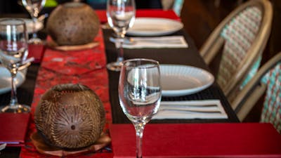 black tablecloth, red batik table runner, coconut shell carved candles and rattan chairs, warm light