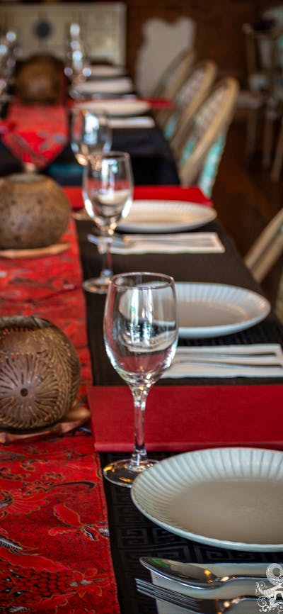 black tablecloth, red batik table runner, coconut shell carved candles and rattan chairs, warm light