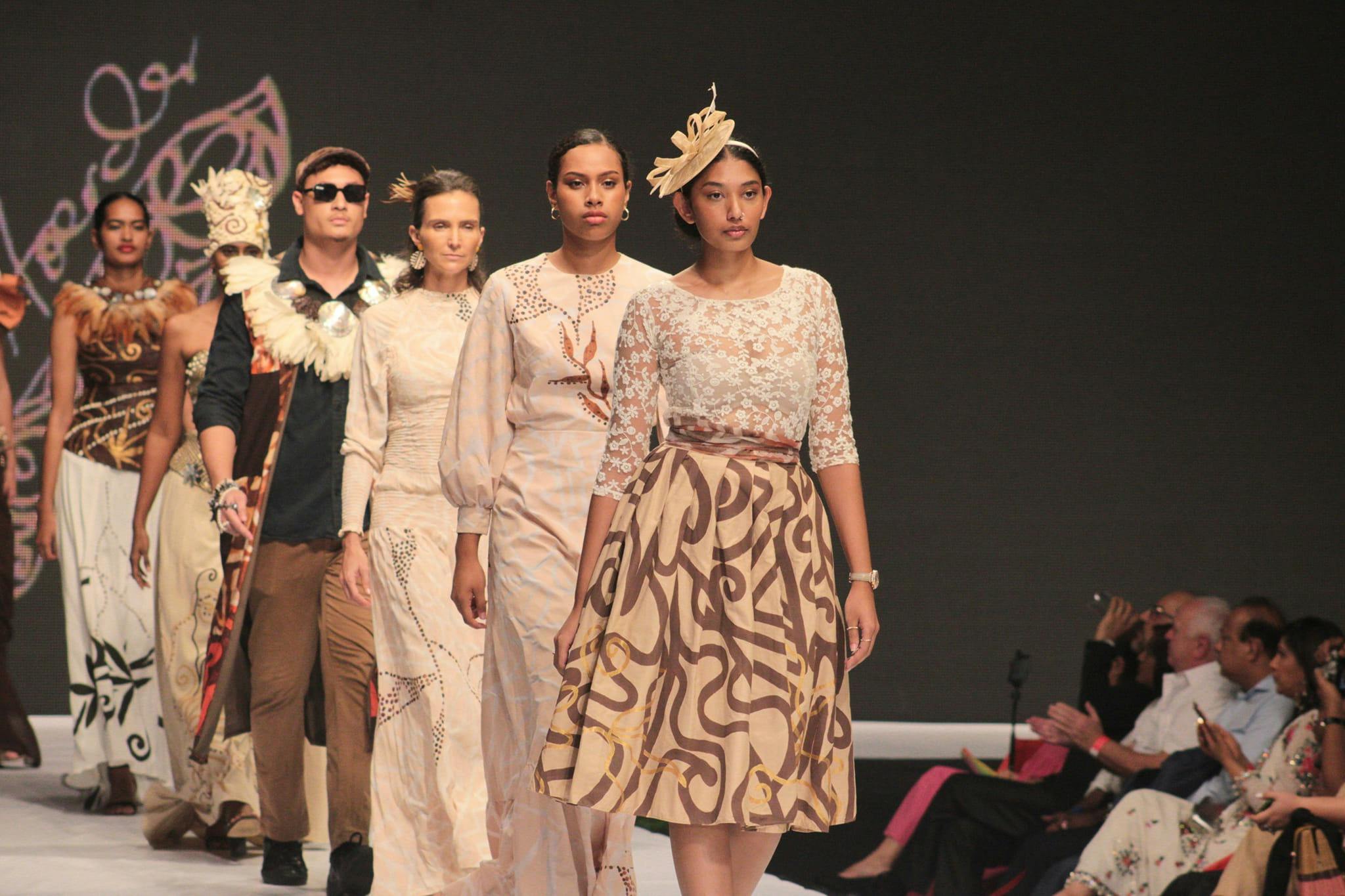 A line of people in fashionable clothing on a runway.