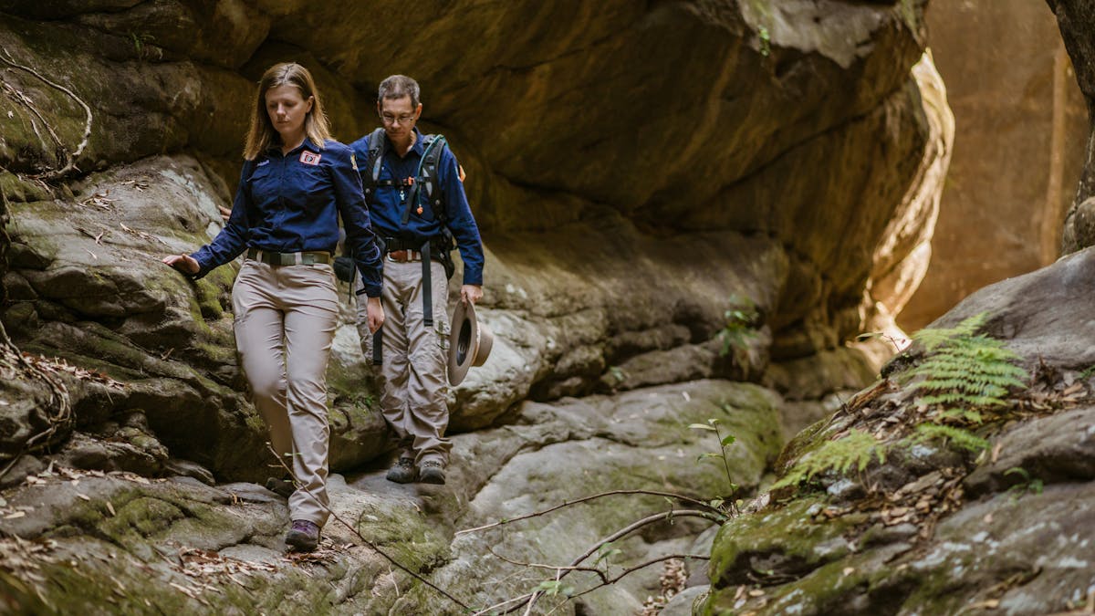 Two tour guides walking through a sandstone slot canyon at Carnarvon Gorge.