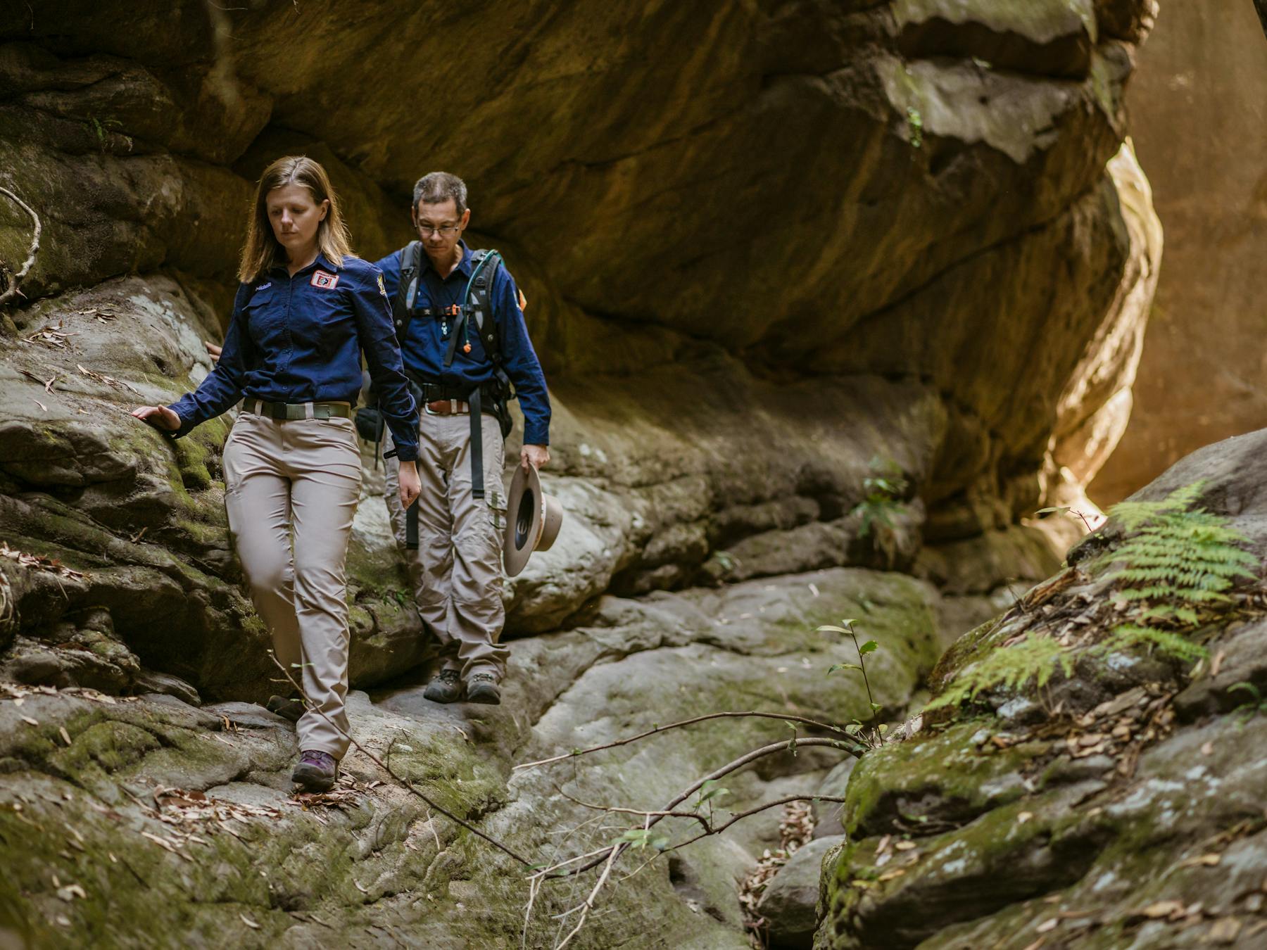 Two tour guides walking through a sandstone slot canyon at Carnarvon Gorge.
