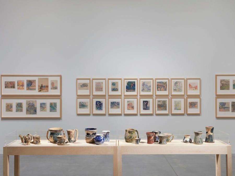 A selection of ceramics by Merric Boyd with framed coloured drawings behind