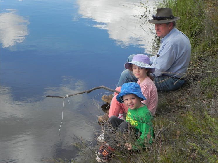 Man and two children fishing by stream