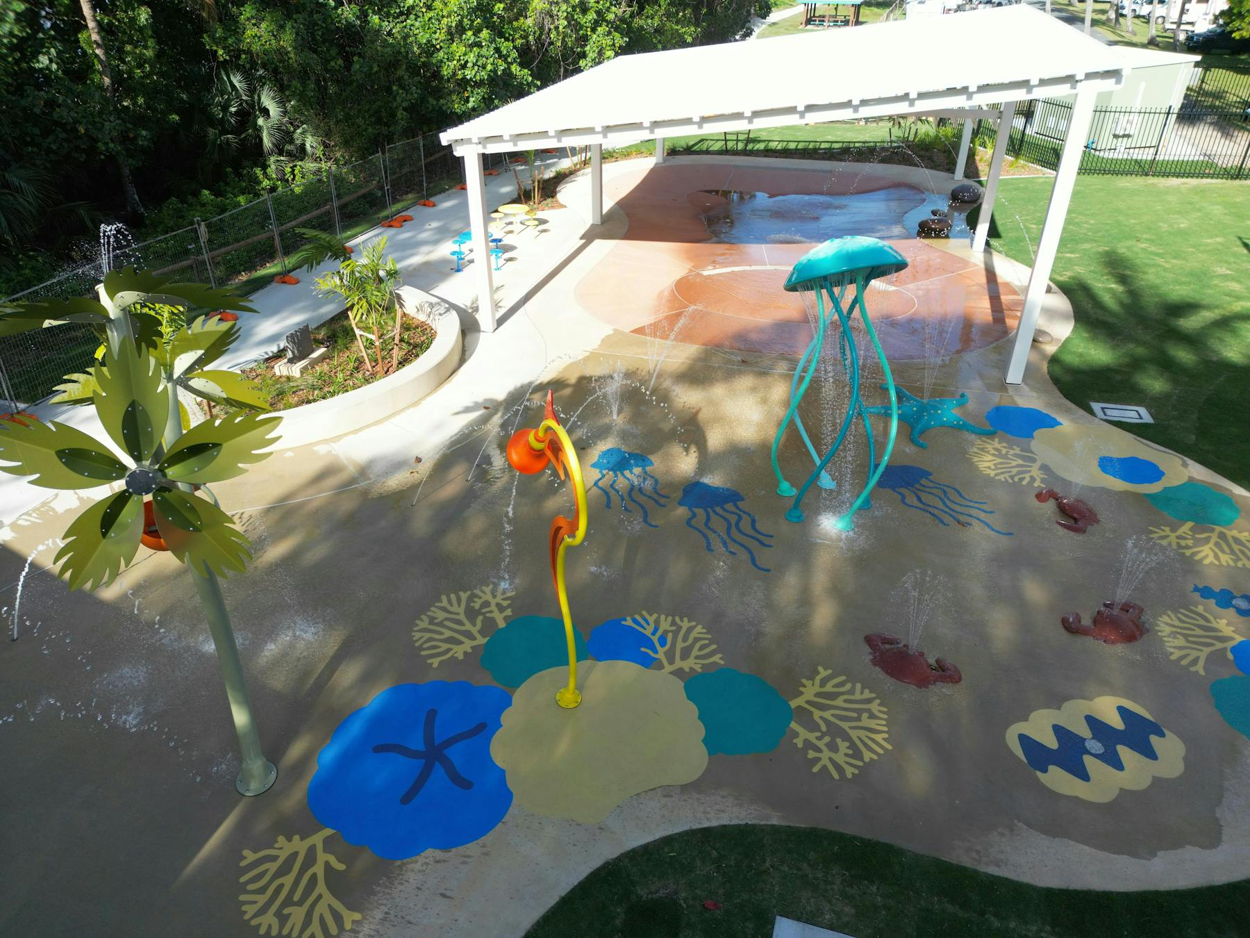 Water Park features, painting on the ground, hade over the wading pool, tress and the grass area.