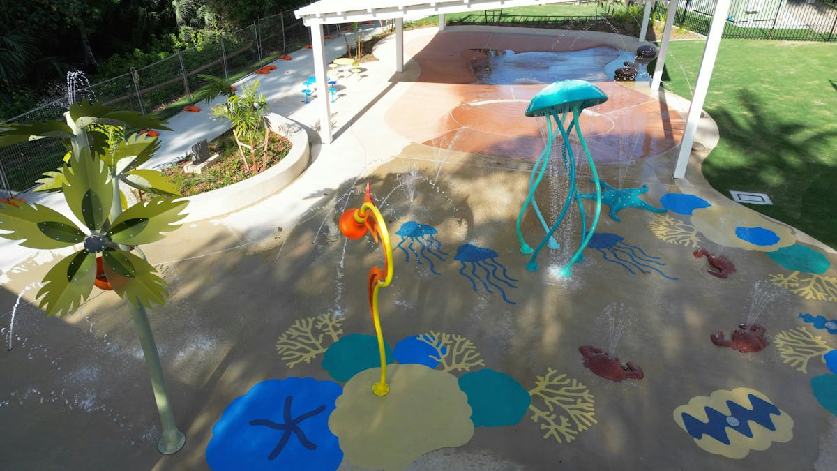 Water Park features, painting on the ground, hade over the wading pool, tress and the grass area.
