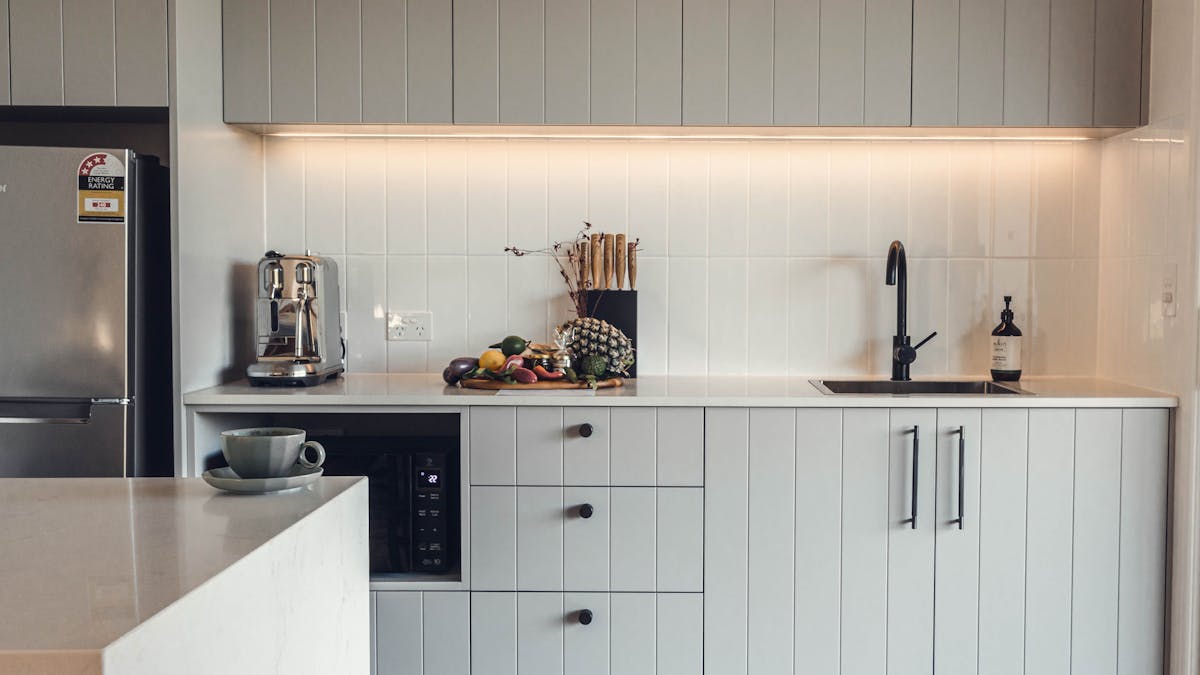 Kitchenette with coffee machine, fridge, microwave, sink, knife block and fresh produce on the bench