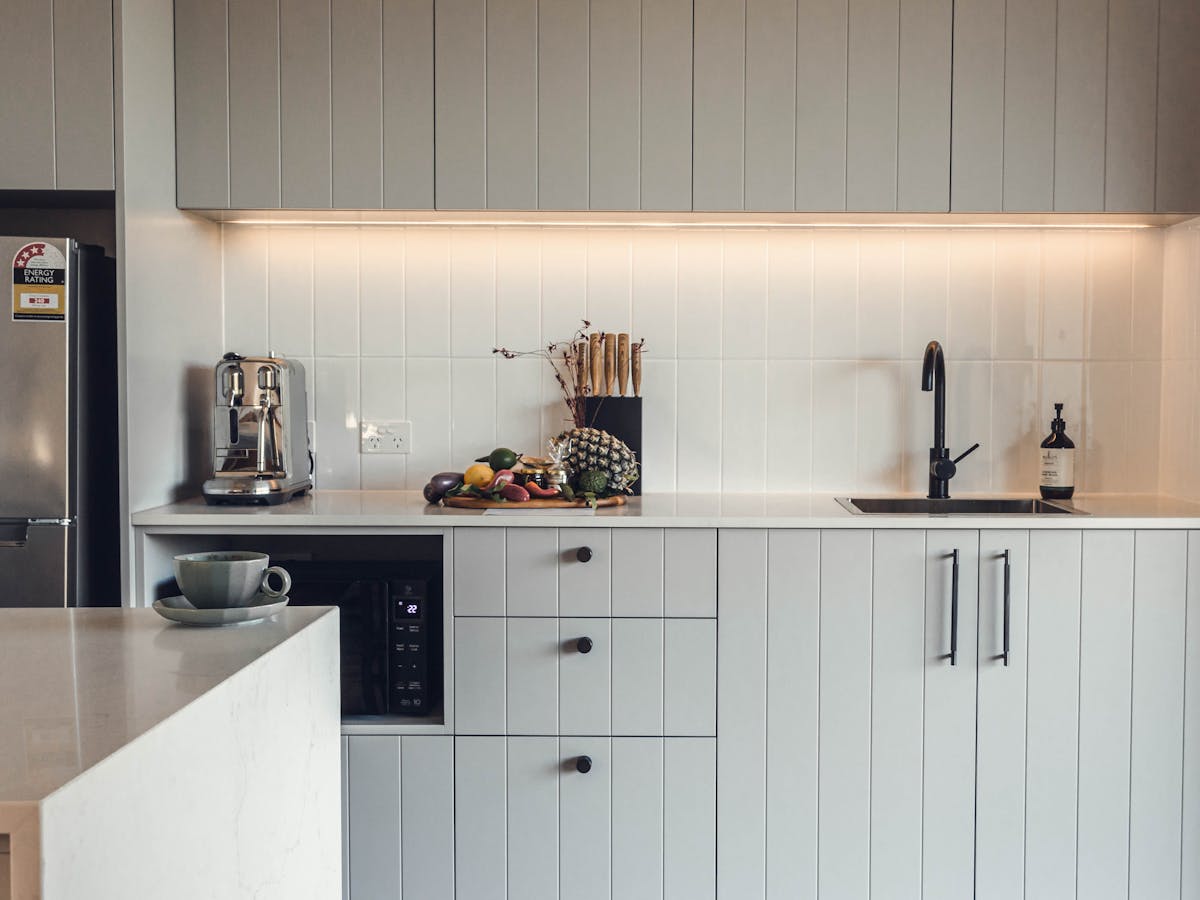Kitchenette with coffee machine, fridge, microwave, sink, knife block and fresh produce on the bench
