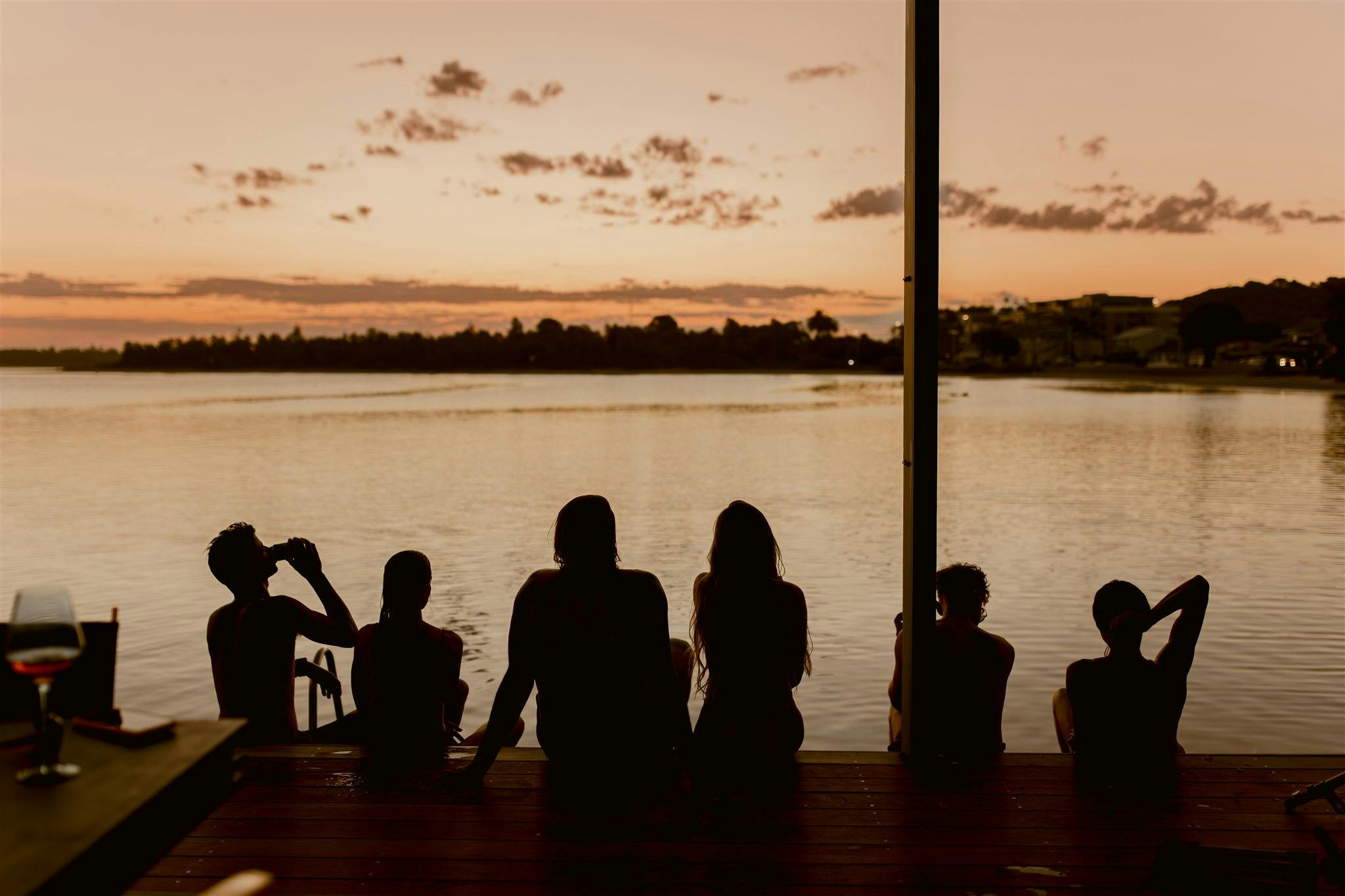 People sitting on the deck and looking at the sunset over the lake