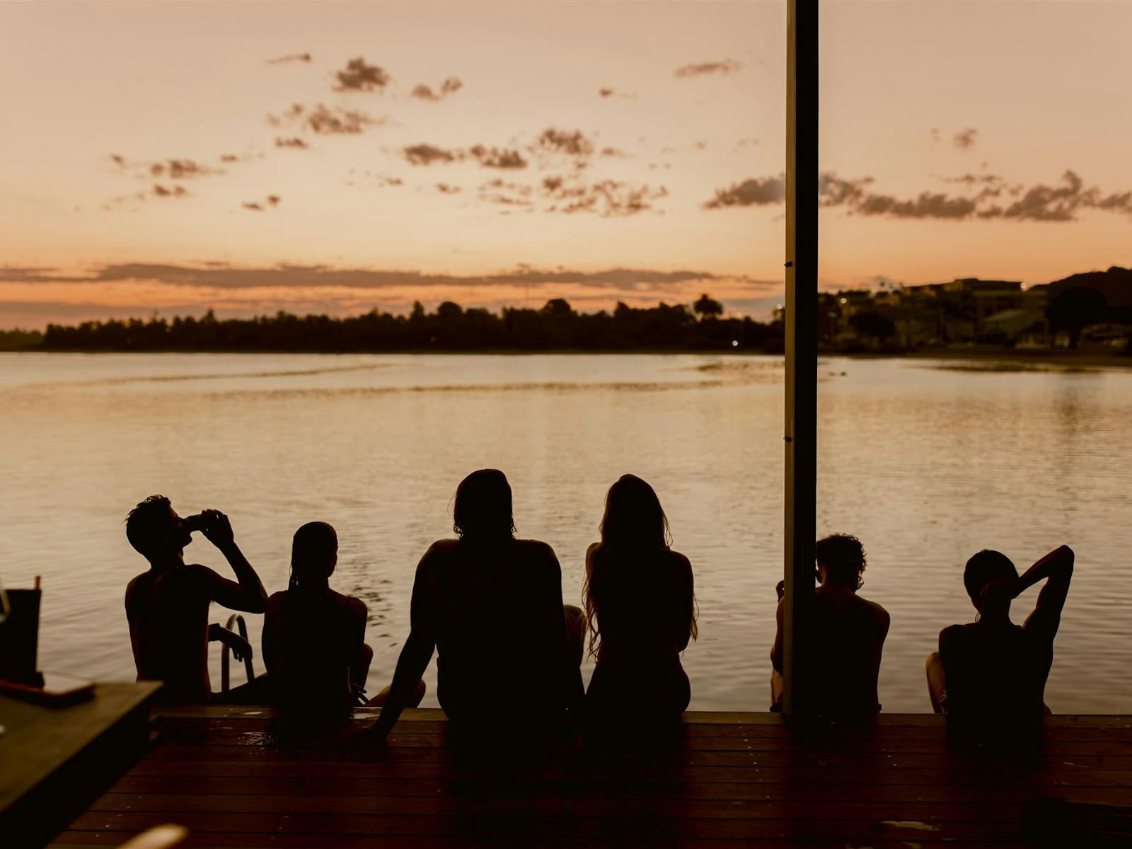 People sitting on the deck and looking at the sunset over the lake