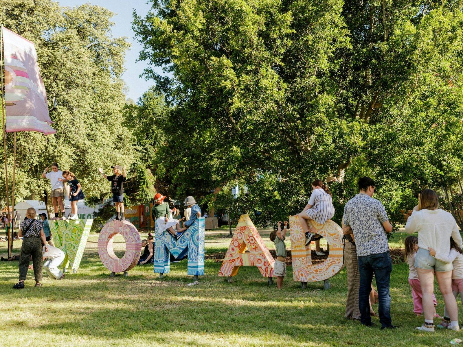 WOMAD colourful letters in park with people surrounding them