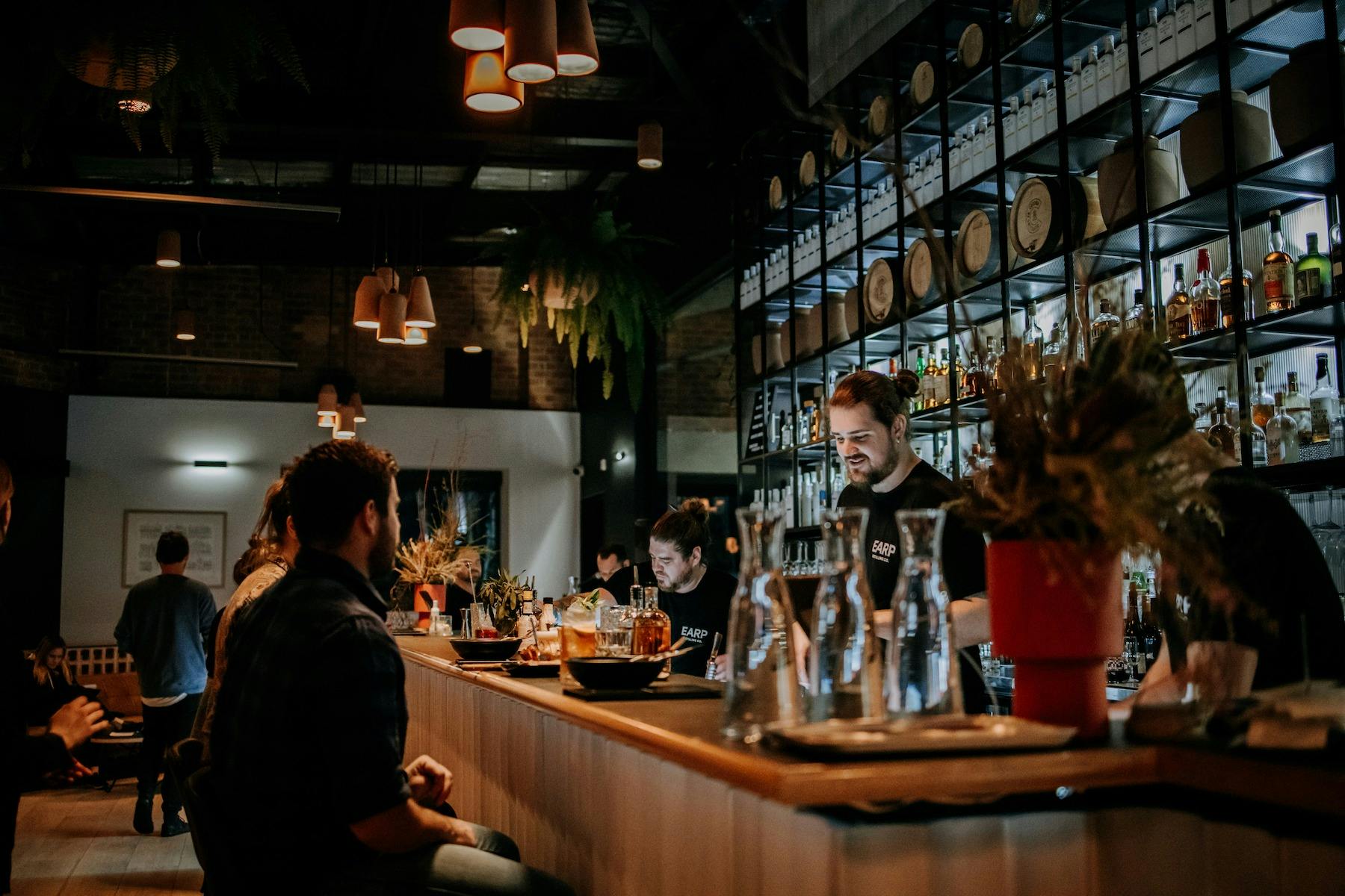 우리 증류소 바에 앉아서 음식을 제공받고 있는 고객들의 야간 촬영