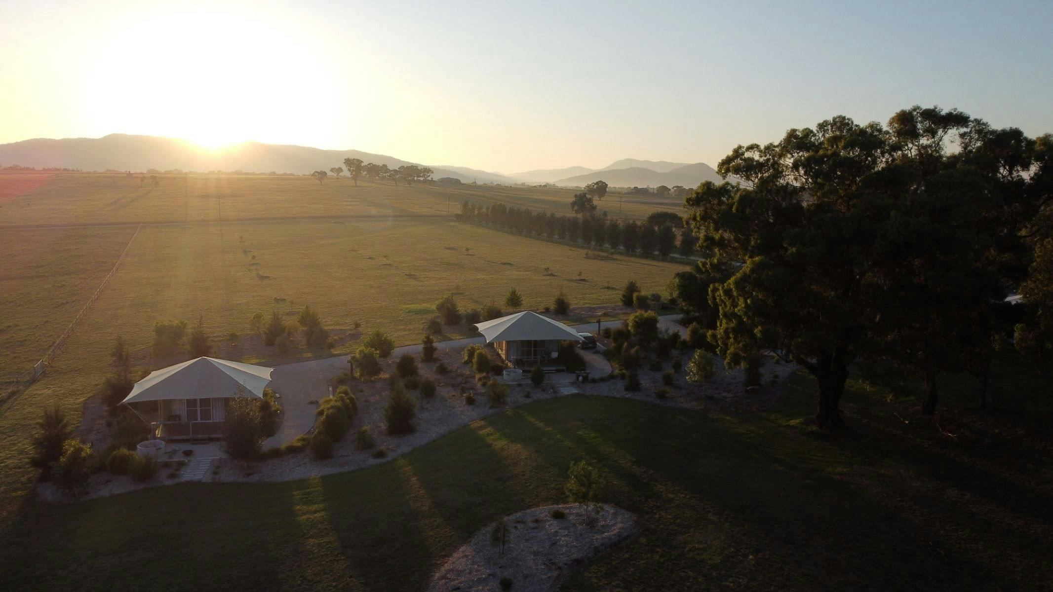 Sun rising over the hills overlooking eco glamping tents and landscape
