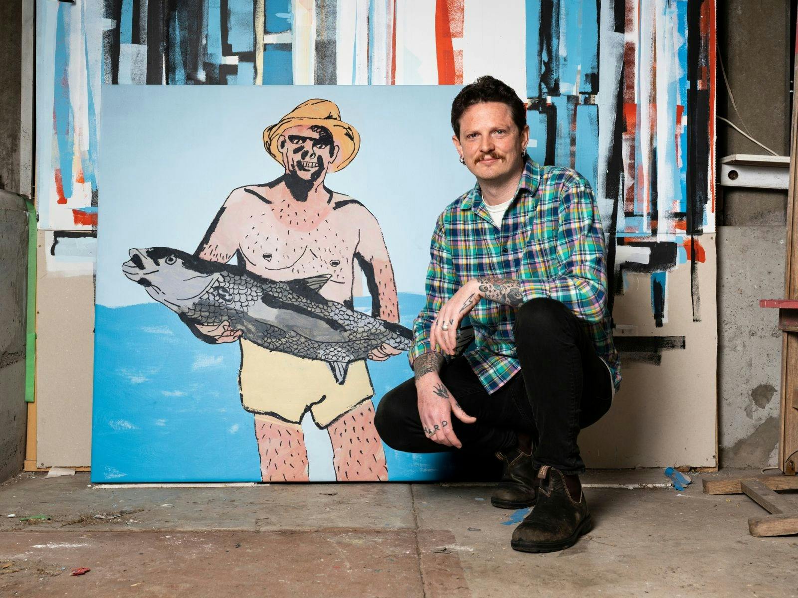 Image of a man kneeling in front of a painting of a man holding a fish.