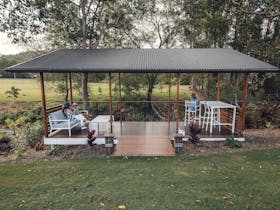 Covered picnic area with lounge and table setting overlooking the duck pond