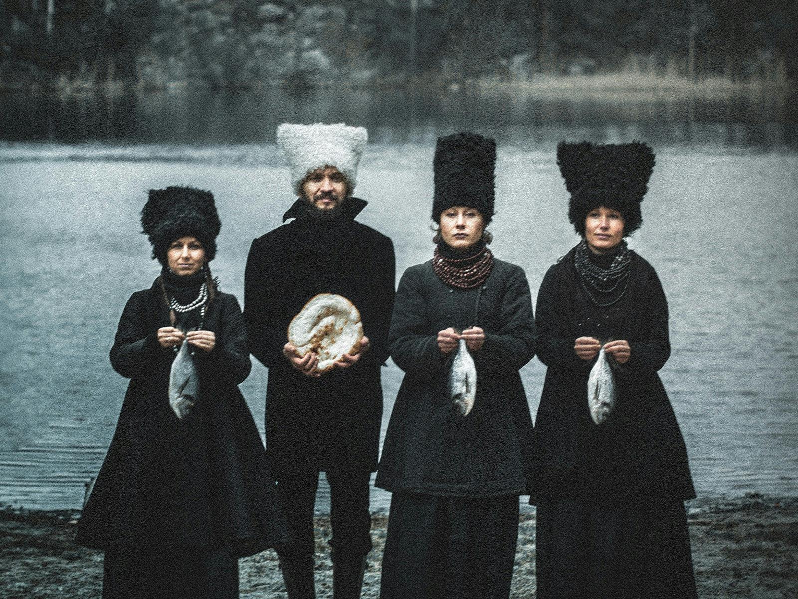 Four people standing by lake each holding a fish