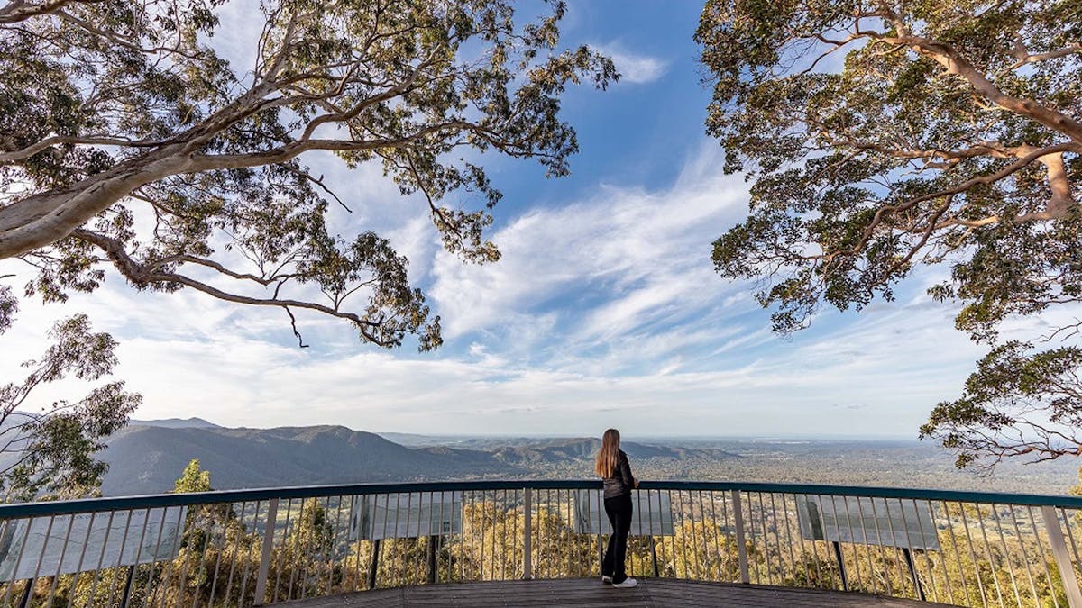 Woman standing on a deck looking at view of mountains and valley