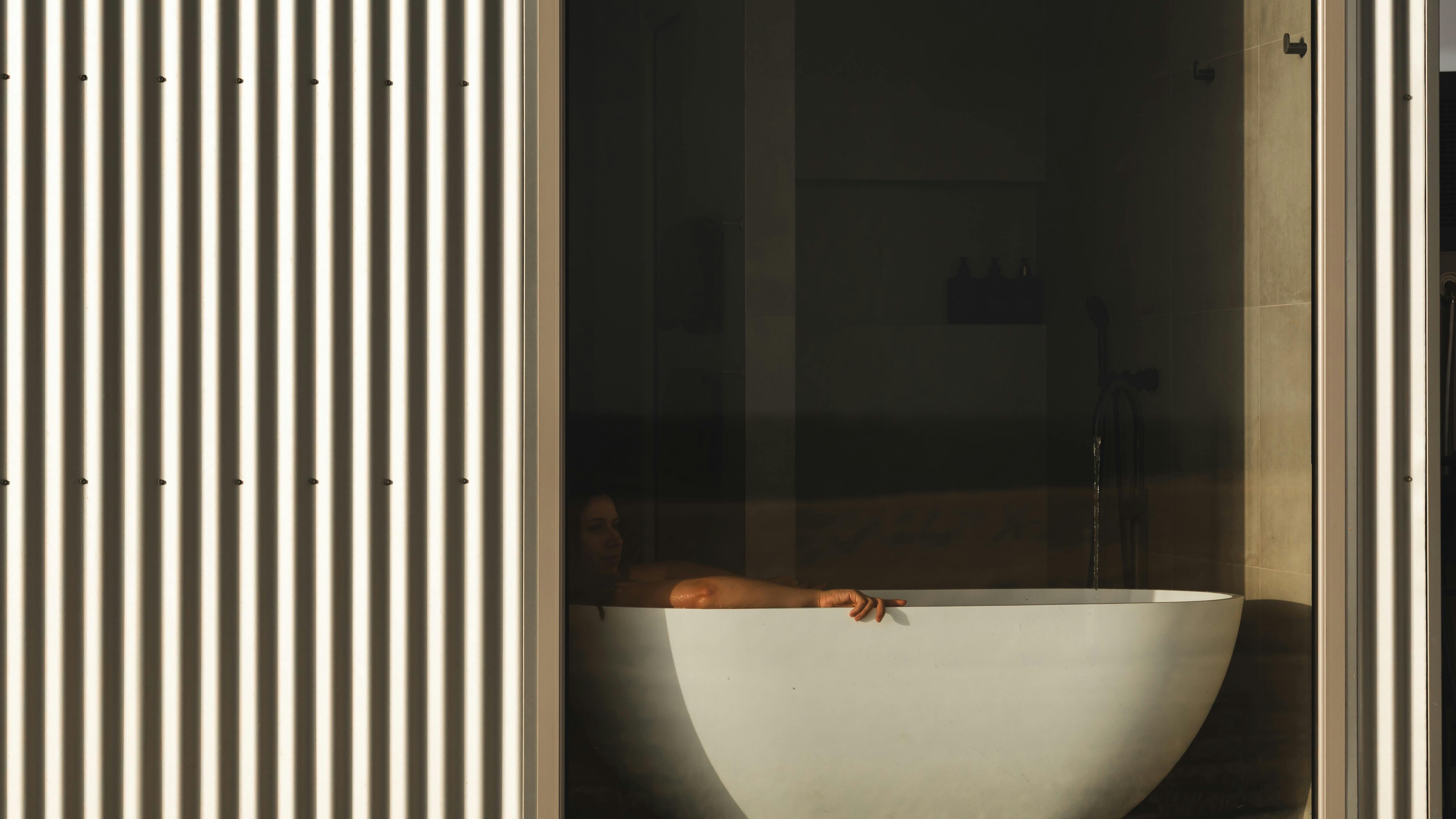 Looking inside the bathroom to girl having a bath