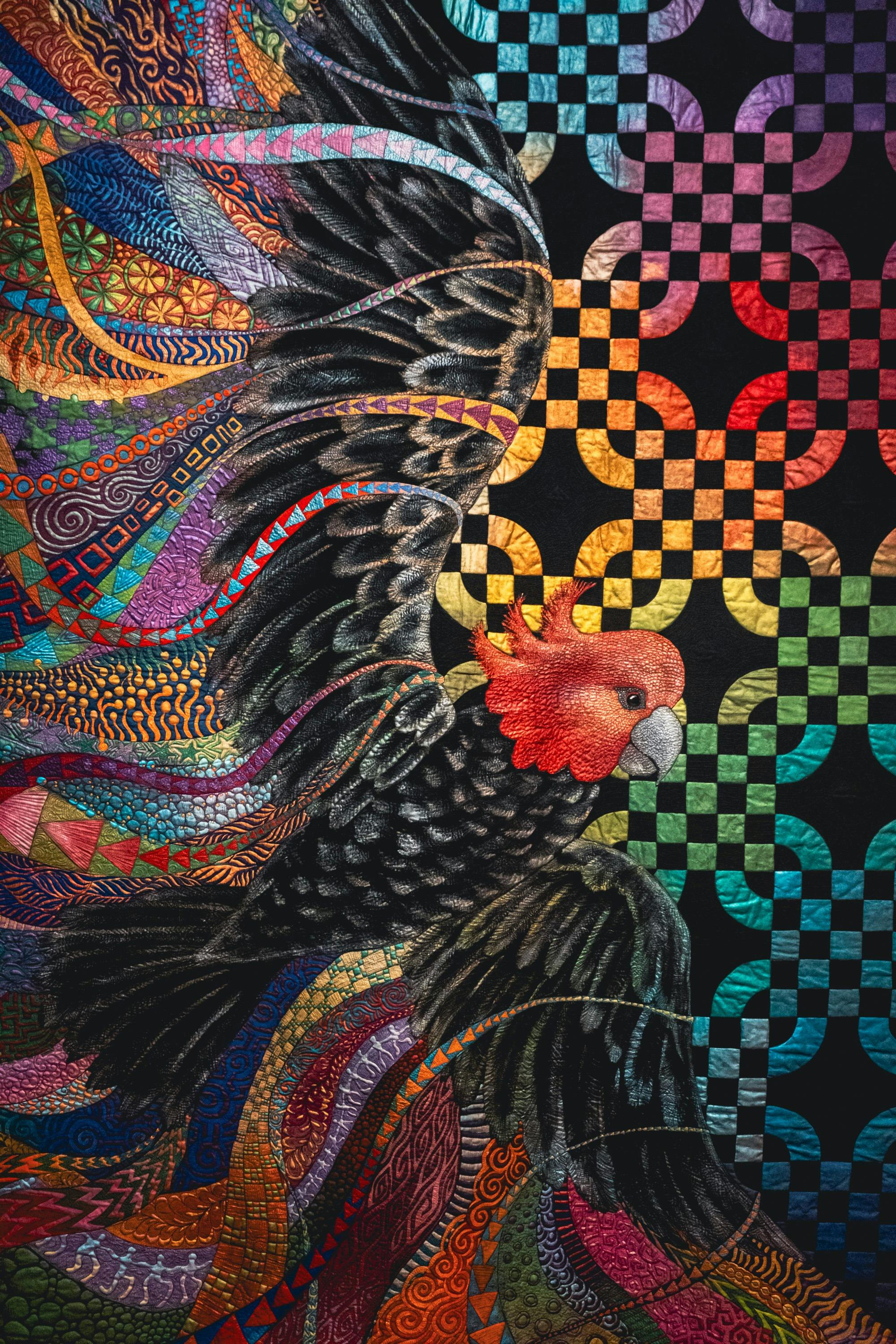 Freedom quilt by Helen Godden of a gang-gang cockatoo in flight with bright details surrounding