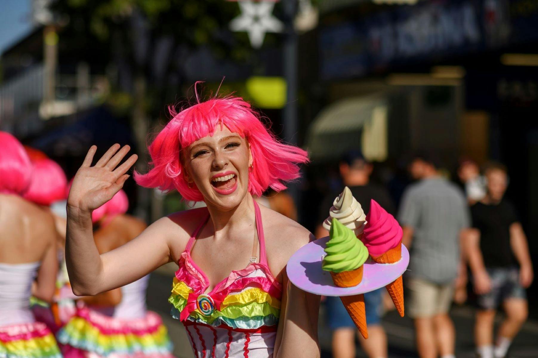 Woman in pink wig waving to the camera and holding ice cream props