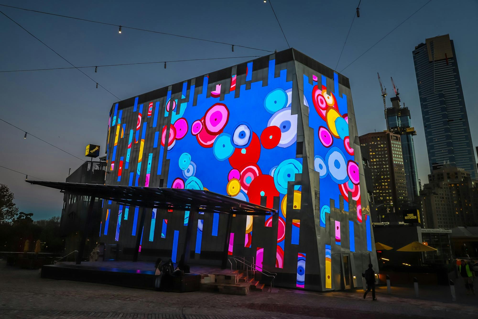 The Fed Square Big Screen is lit up with brightly coloured digital art by artist Sally Gabori.