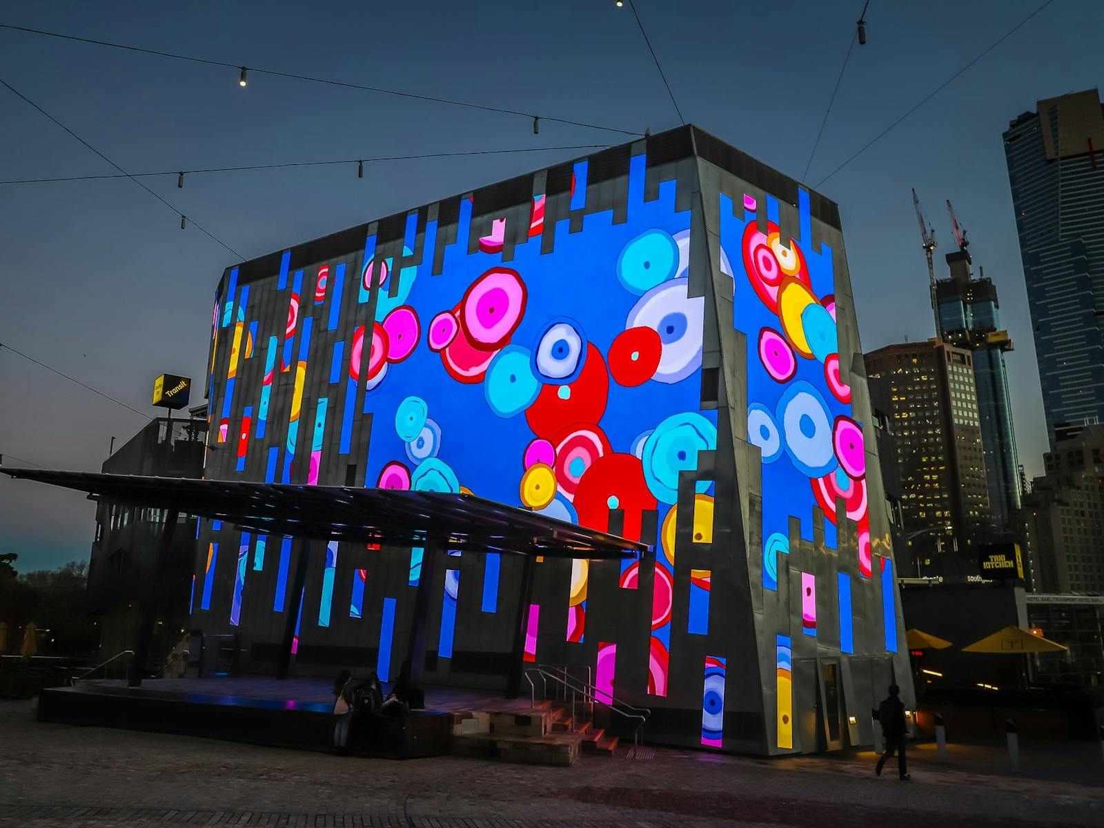 The Fed Square Big Screen is lit up with brightly coloured digital art by artist Sally Gabori.