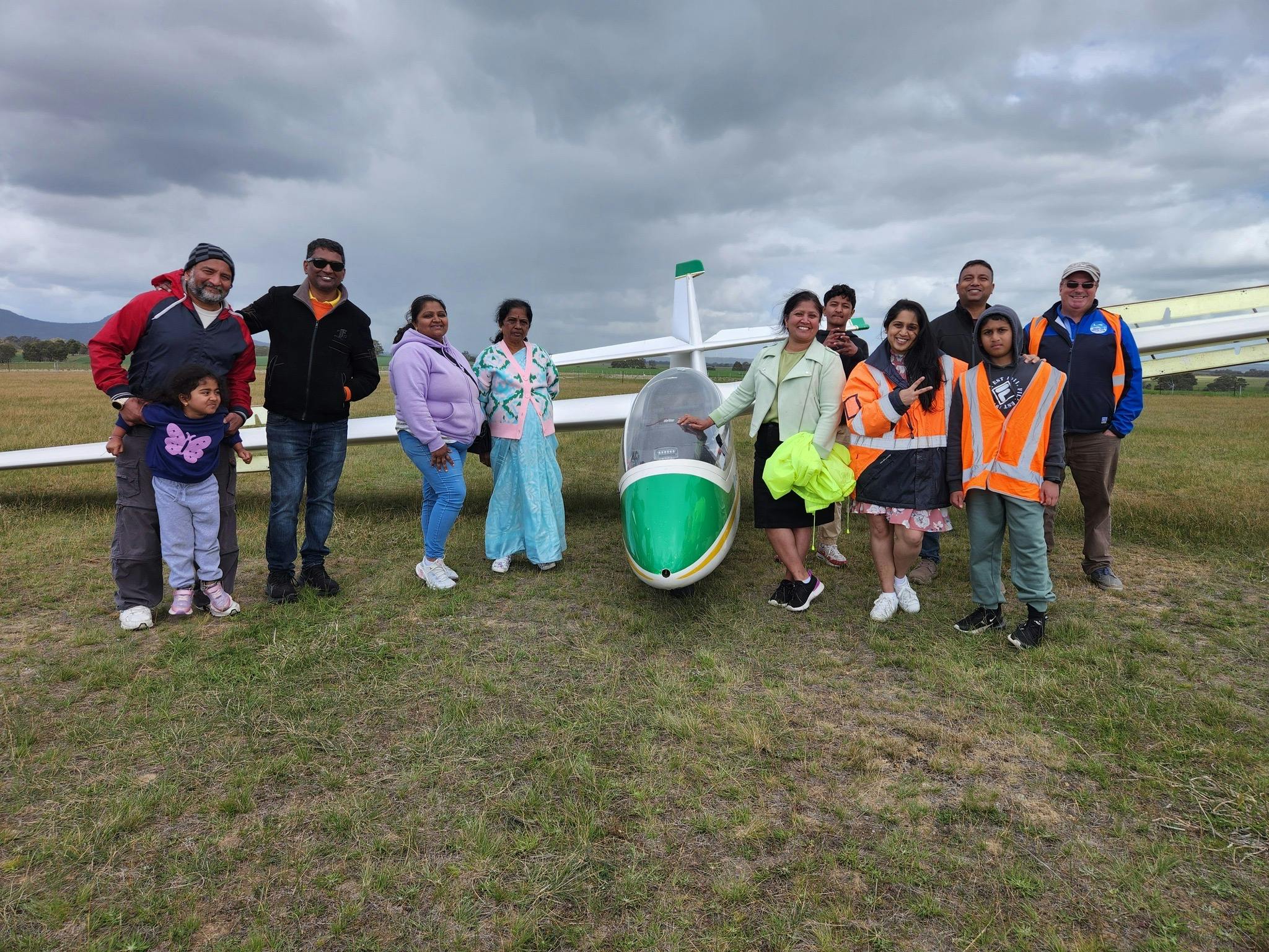 Eleven people standing in front of a small plane on a runway