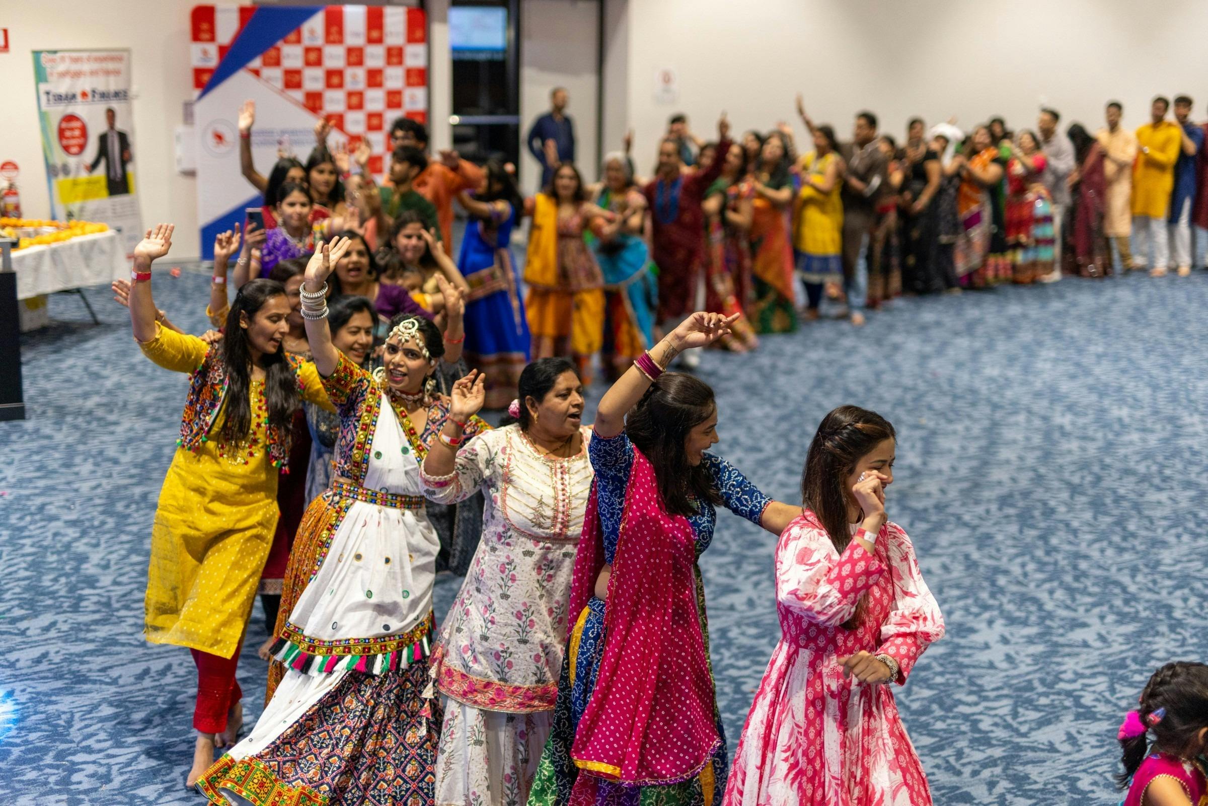 Crowd in colourful traditional outfits dancing Garba in a circle at a Navratri night in Perth