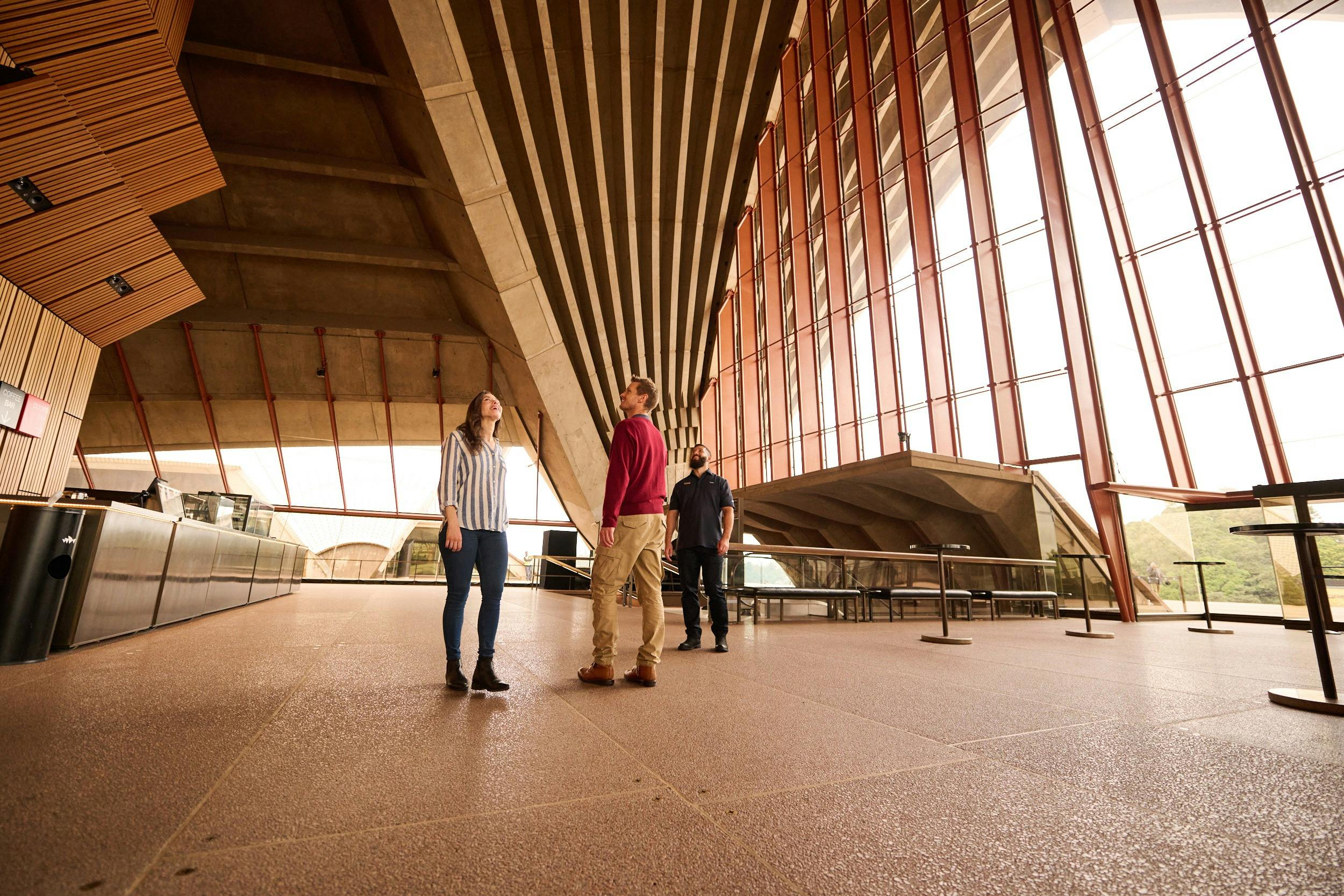 Tour guide, a man and a woman looking up at the cathedral ceiling of the Concert Hall Southern Foyer