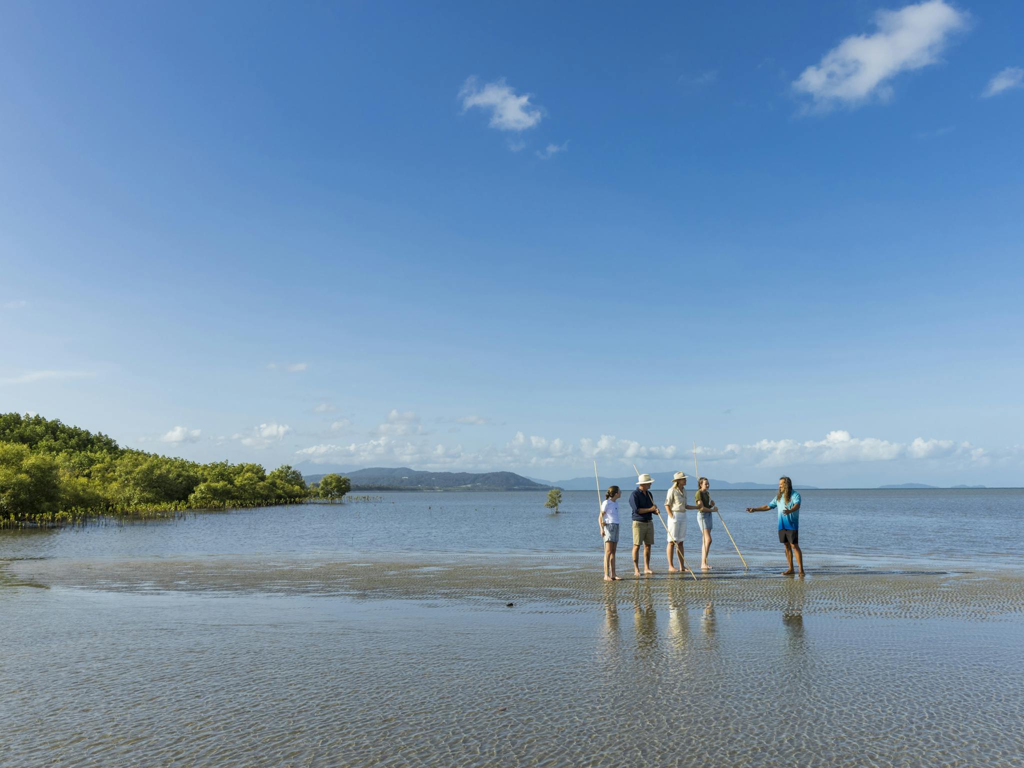 small group holding traditional aboriginal spears on remote beach with Kubirri Warra clan member small group holding traditional aboriginal spears on remote beach with Kubirri Warra clan member