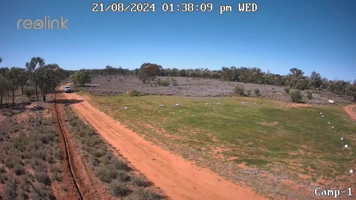 Car driving on a red dirt acces road into Ticklmans Gardens Car driving on a red dirt acces road into Ticklmans Gardens