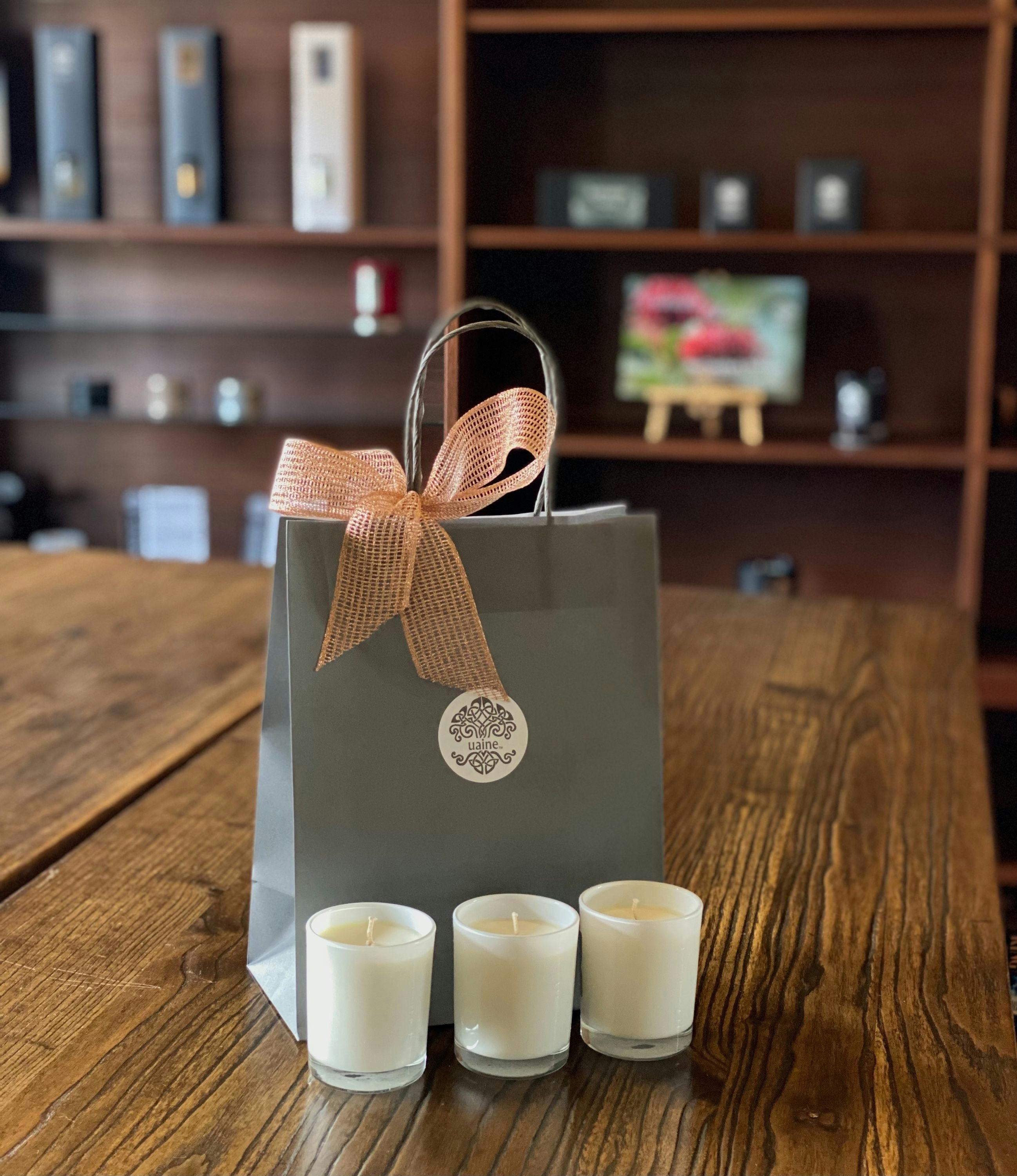 A bag with a ribbon on it. In front of the bag are three white candles.