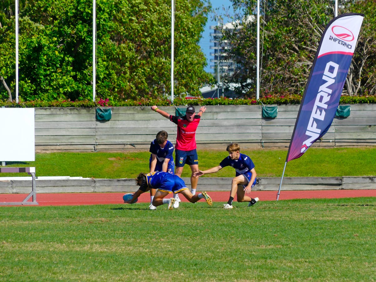 A young male touch player dives to score a try and elude an opposition player.