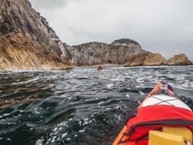 Sea kayakers paddling outside the Breaksea Islands on Port Davey in Southwest Tasmania