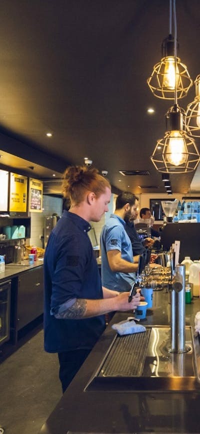 Wait staff serving drinks behind the bar with customers waiting to collect  drinks