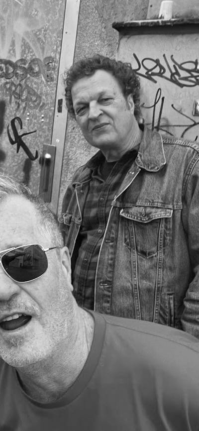 Four men standing in front of a wall with graffiti
